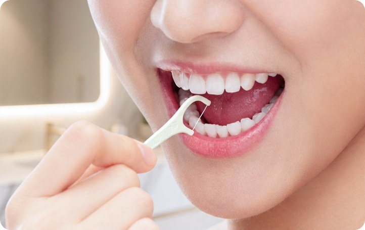 Using an EtsonFloss dental floss pick to clean teeth